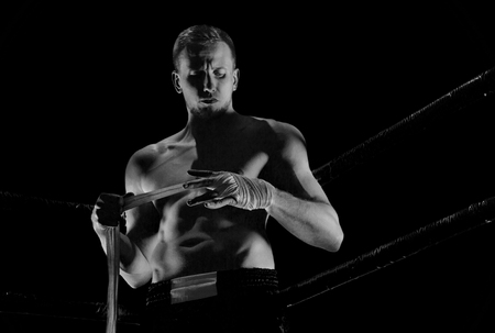 The fighter stands in the corner of the ring and puts bandages on his hands. Mixed fights.の写真素材