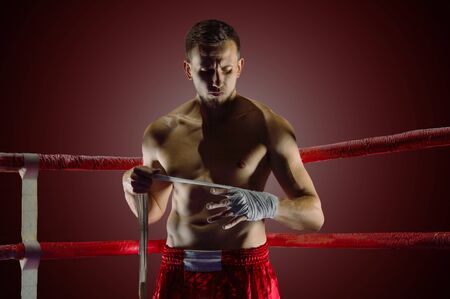 The fighter stands in the corner of the ring and puts bandages on his hands. Mixed fights.の写真素材