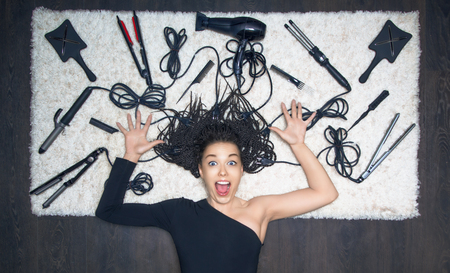 The charming girl spread her hands to the side and screams. Against the backdrop of the tools for creating a haircutの写真素材
