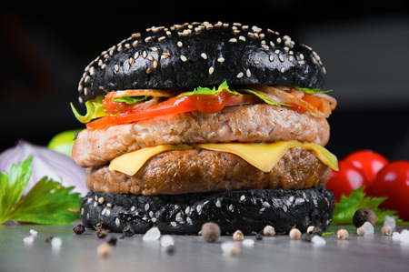 Delicious black juicy burger with fresh tomatoes, peppers and herbs. Mixed mediaの写真素材