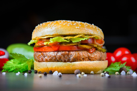 Delicious juicy burger with fresh tomatoes, peppers and herbs. Mixed mediaの写真素材