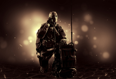 The soldier of the special unit in military uniform sits near the satellite communications apparatus and causes support. Mixed mediaの写真素材