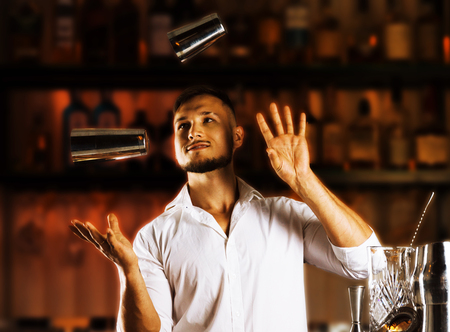 Fantastically beautiful bartender tosses two shakers into the air and arranges a real show for their guests. Mixed mediaの写真素材