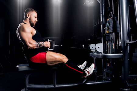 The athlete performs an exercise on the latissimus muscles of the back on a special device. Side viewの写真素材