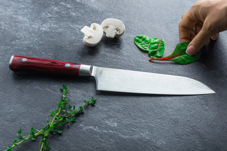 Japanese knife made of Damascus steel lies on a table near the vegetables. View from above