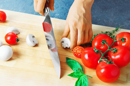 Professional chef cuts vegetables with a sharp knife from Damascus steel. Mixed mediaの写真素材