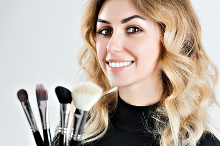 Charming stylist holds four professional brushes for applying makeup. Mixed mediaの写真素材