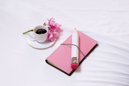 
View from above. The concept of tenderness, care and love. Pink diary, a large white pencil, a cup of coffee and flowers. Mixed mediaの写真素材