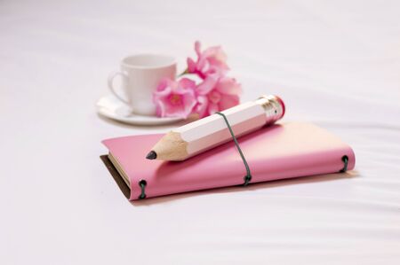 The concept of tenderness, care and love. Pink diary, a large white pencil, a cup of coffee and flowers. Mixed mediaの写真素材