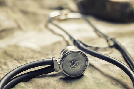 Stethoscope lies on the uniform of a US soldier. The concept of health care, military insurance, state care. Top view. Mixed mediaの写真素材