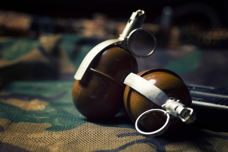 Two grenades lie on a camouflage background. The concept of military operations, political...