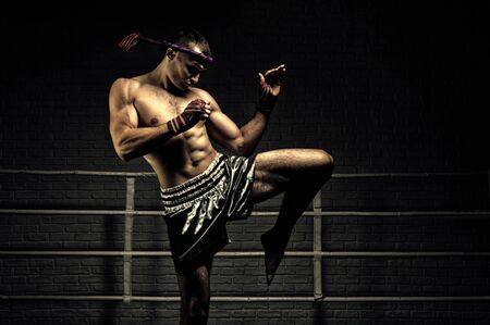 Kickboxer in the ring surrounded by searchlights stretches before the fight. Makes swing movements with his knee. Mongkhon. Mixed mediaの写真素材