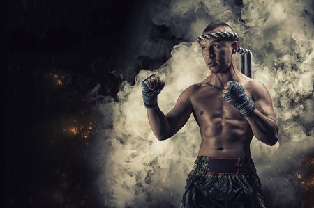 Portrait of a boxer of mixed martial arts standing on the background of smoke and fire. The concept of sports, mma, kickboxing. Mixed mediaの写真素材