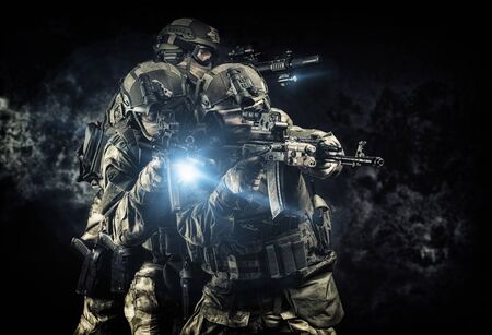 American soldiers in combat ammunition with weapons in the hands of equipped laser sights are in battle order. Mixed mediaの写真素材