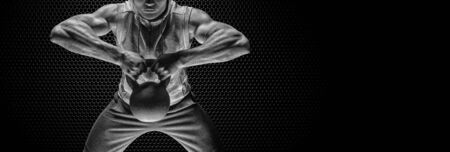 Athlete posing with kettlebell in the gym. The concept of crossfit, healthy lifestyle, sports. Mixed mediaの写真素材