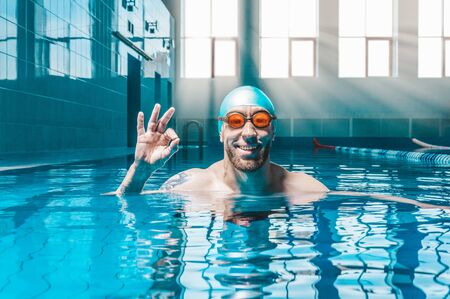 Portrait of a man in the pool. He is wearing huge funny glasses. Water sports concept. Mixed mediaの写真素材