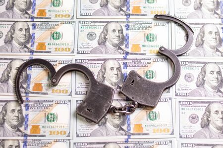 Handcuffs on the background of hundred-dollar bills. Illegal trade. Justice concept. Mixed mediaの写真素材
