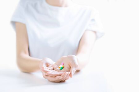 Woman in hospital clothes holds a set of pills in her palms. The concept of unstable psyche, taking antidepressants. Mixed Mediaの写真素材