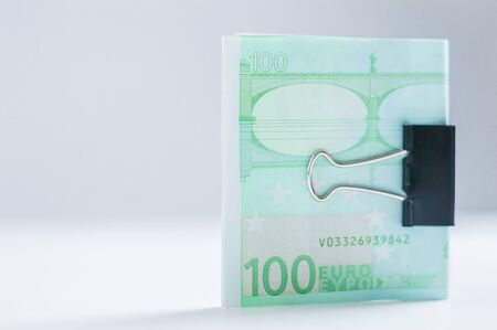 Pack of euro notes lies on a white table fastened with a paperclip. The concept of savings during the crisis. Mixed mediaの写真素材