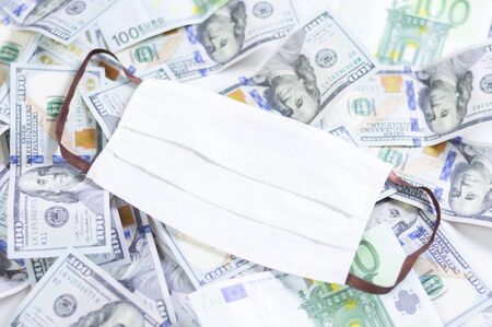 Medical mask rests on one hundred dollar bills. The concept of an epidemic, paid medicine, lack of equipment for doctors. Mixed mediaの写真素材