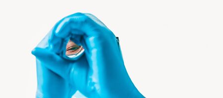 Portrait of a doctor on a white background. He is looking through his hands. Medicine concept. Mixed mediaの写真素材