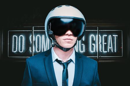 Portrait of a man in a suit and helmet. He stands against a wall with a neon sign. Business concept. Mixed mediaの写真素材