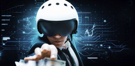 Portrait of a businessman in a suit and aviator helmet. He is trying to reach a pack of hundred-dollar bills. Business concept. Mixed mediaの写真素材