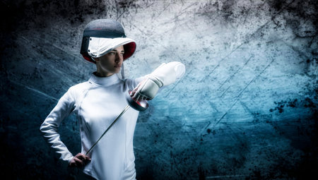 Charming girl dressed as a fencer posing with a mask and a sword. The concept of fencing. Mixed...