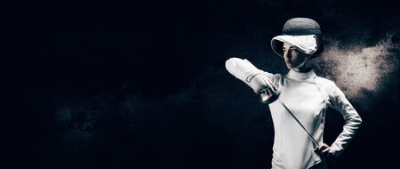 Charming girl dressed as a fencer posing with a mask and a sword. The concept of fencing. Mixed mediaの写真素材