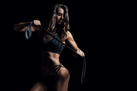 Beautiful girl posing with a gymnastic elastic band on a black background. Sports, fitness and...