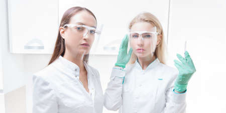 Portrait of two girls in white coats. The concept of cosmetology, plastic surgery, beauty industry. Mixed mediaの写真素材