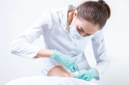 The beautician washes the patient's face before peeling. Skin care concept. Mixed mediaの写真素材