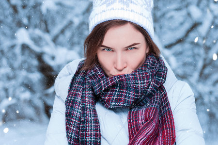 Beautiful girl with a displeased expression on the background of snowy trees. Snowball game. Christmas holidays concept. Mixed mediaの写真素材