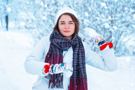Portrait of a beautiful girl throwing a snowball. Concept for Christmas holidays, winter games, happiness and fun. Mixed mediaの写真素材