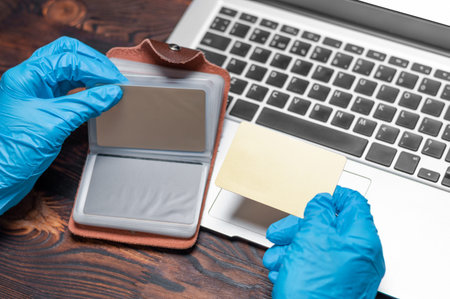 Image of hands in medical gloves on the background of a laptop. The woman holds a plastic bank card...
