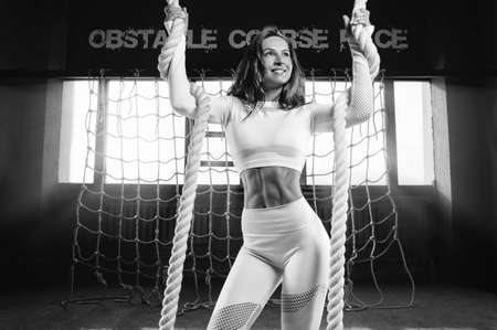 Beautiful girl gymnast warming up in the athletic hall. Exercises with ropes. Fitness concept. Mixed mediaの写真素材
