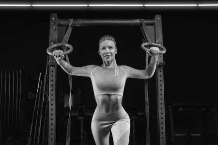 Beautiful tall blonde is training on athletic rings. Fitness and bodybuilding concept. Mixed mediaの写真素材