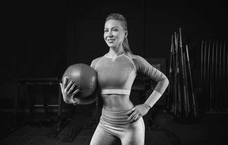 Charming blonde posing in the gym with a fitness ball. Front view. The concept of sports, bodybuilding, fitness. Mixed mediaの写真素材