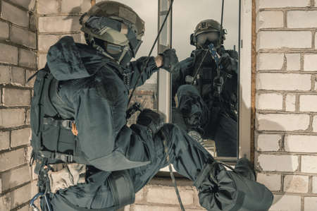 Group of special forces fighters storm the building through the window. Training sessions of the SWAT team. Anti-terror concept. Climbers. Mixed mediaの写真素材