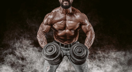 Muscular athlete lifts dumbbells. Shoulder pumping. Fitness and bodybuilding concept. Mixed media