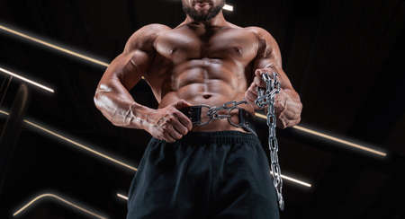 Muscular man posing in the gym with an athletic belt. Fitness concept. Mixed mediaの写真素材