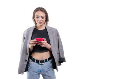 Portrait of a beautiful girl in a jacket with a mobile phone in hand. White background. Mixed mediaの写真素材