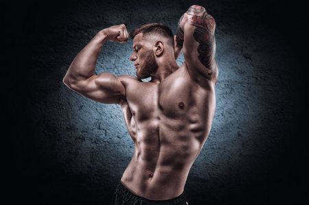 Young muscular guy with a nice abs posing against the backdrop of a blue spot. Fitness and nutrition...