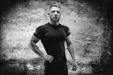 Young muscular guy posing against the background of a concrete wall. Fitness and nutrition concept. Mixed mediaの写真素材