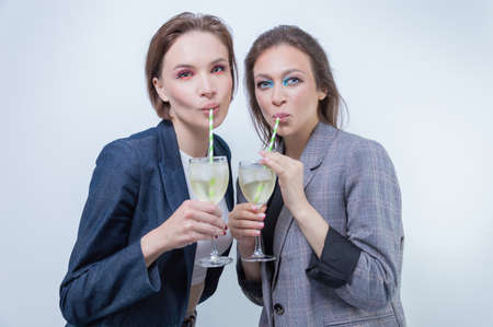 Portrait of two business women in jackets with glasses in their hands. Successful business deals celebration concept. Mixed mediaの写真素材