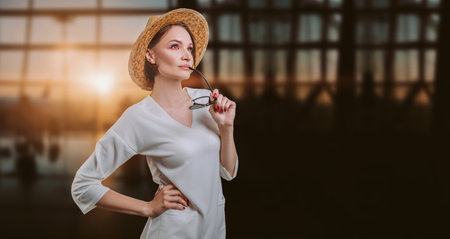 Portrait of a beautiful woman in a yellow hat standing at the airport with a passport and ticket....