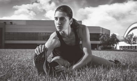 Beautiful young runner warms up on the soccer field before the race. Sports concept. Mixed mediaの写真素材