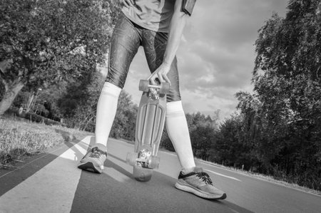 The girl holds a skateboard in her hands. Track in the park. Sports concept. Mixed media