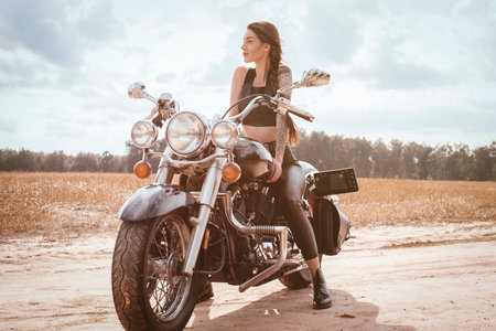 Young sexy girl posing on a motorcycle at sunset. Motor sport concept. Mixed mediaの写真素材