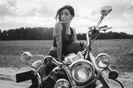 Young sexy girl posing on a motorcycle at sunset. Motor sport concept. Mixed media